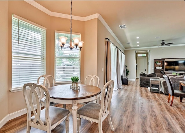 dining space with ornamental molding, ceiling fan with notable chandelier, and light wood-type flooring