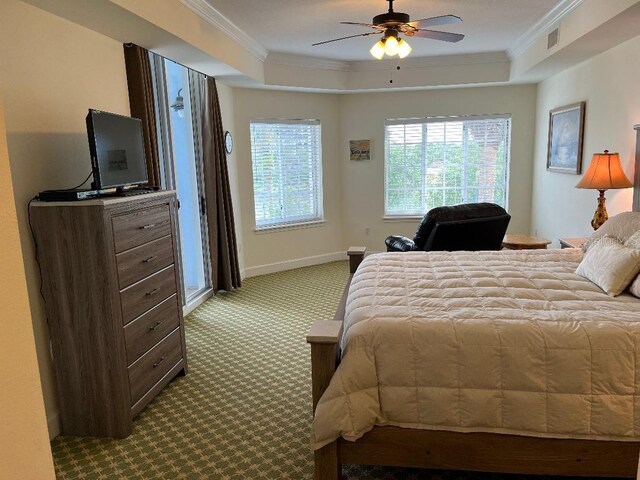 carpeted bedroom featuring a raised ceiling, ornamental molding, and ceiling fan