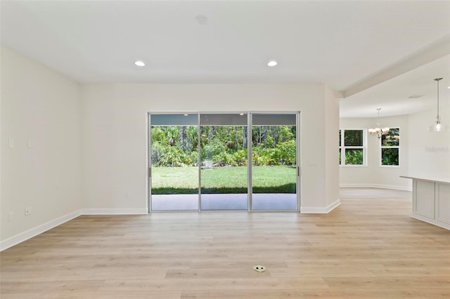 unfurnished room with light wood-type flooring and a chandelier