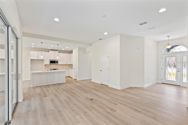 unfurnished living room with light wood-type flooring and sink