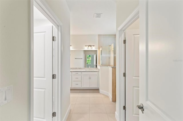 bathroom with a tile shower, tile patterned flooring, and vanity