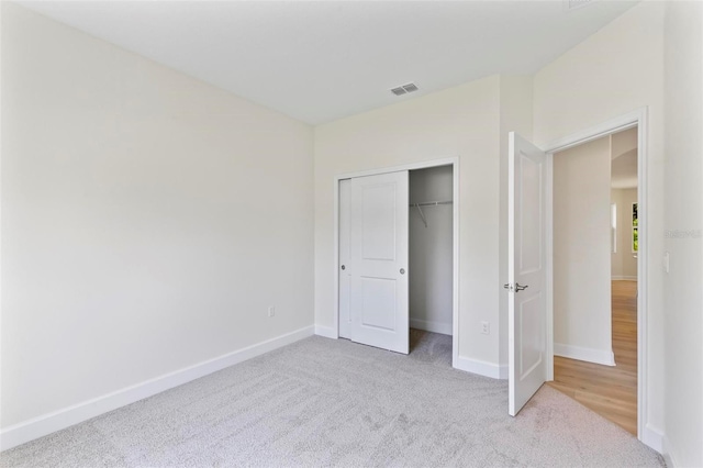 unfurnished bedroom featuring light carpet and a closet