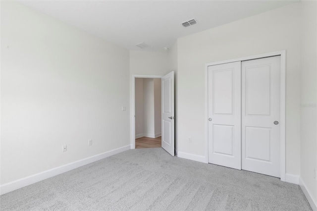 unfurnished bedroom with a closet and light colored carpet