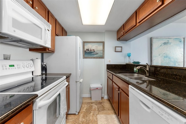 kitchen featuring dark stone counters, light tile flooring, white appliances, and sink