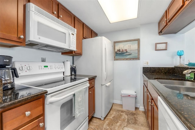 kitchen with light tile flooring, white appliances, sink, and dark stone counters