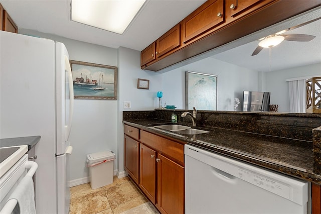 kitchen with light tile floors, ceiling fan, white appliances, dark stone countertops, and sink