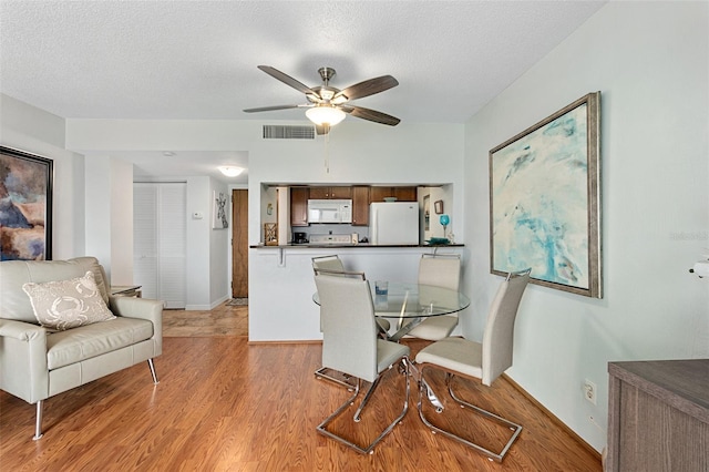 dining room with a textured ceiling, light hardwood / wood-style floors, and ceiling fan