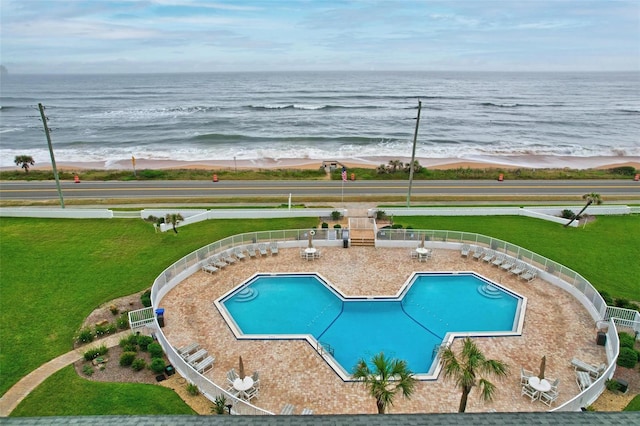 view of swimming pool featuring a lawn and a water view