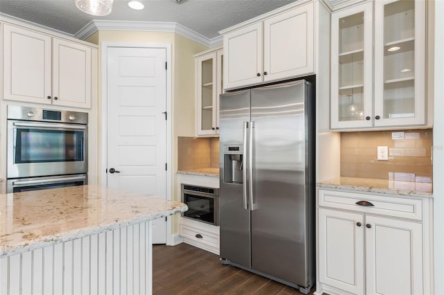 kitchen featuring tasteful backsplash, light stone countertops, stainless steel appliances, and white cabinetry