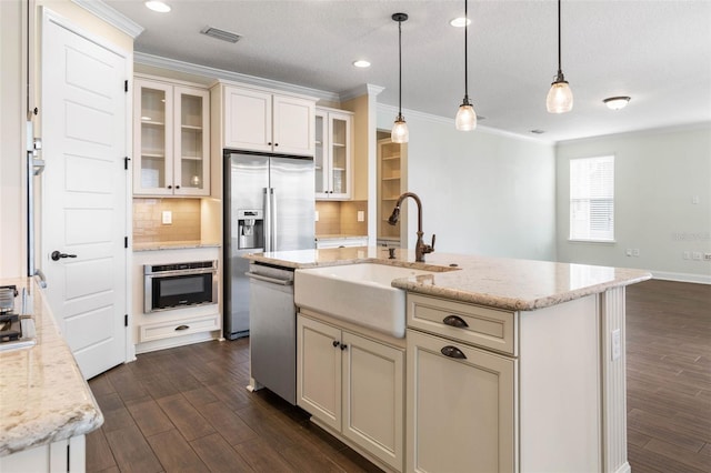 kitchen featuring decorative backsplash, sink, appliances with stainless steel finishes, and a kitchen island with sink