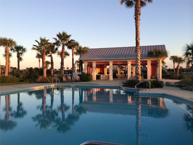 pool at dusk with an outbuilding and a patio