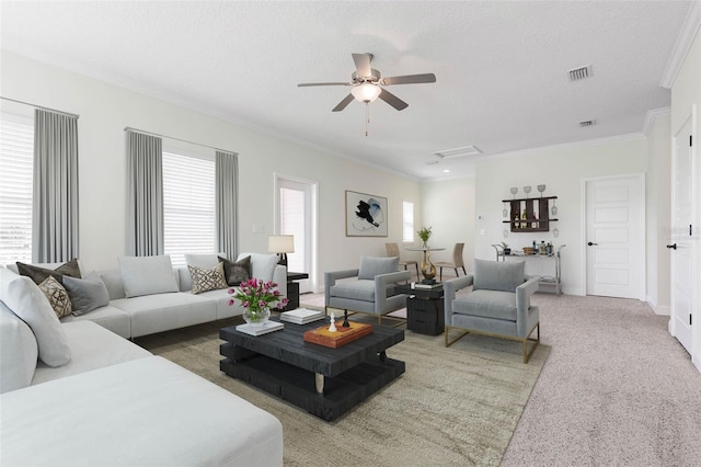 living room featuring carpet floors, a textured ceiling, ornamental molding, and ceiling fan