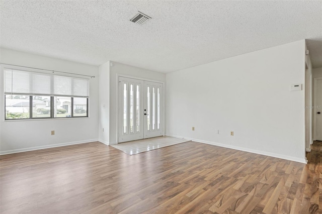 empty room featuring french doors, a textured ceiling, and hardwood / wood-style floors