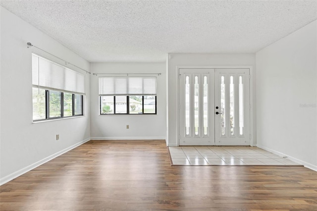 entrance foyer with light tile flooring, a textured ceiling, and french doors