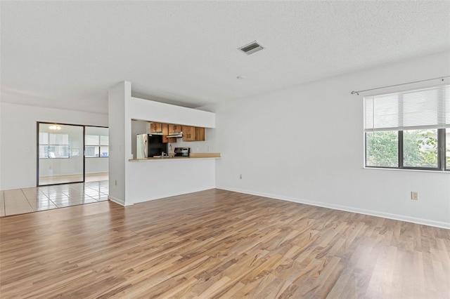 unfurnished living room featuring a textured ceiling and light tile floors