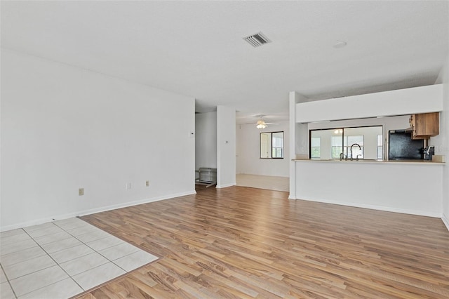 unfurnished living room with ceiling fan, sink, and light hardwood / wood-style floors