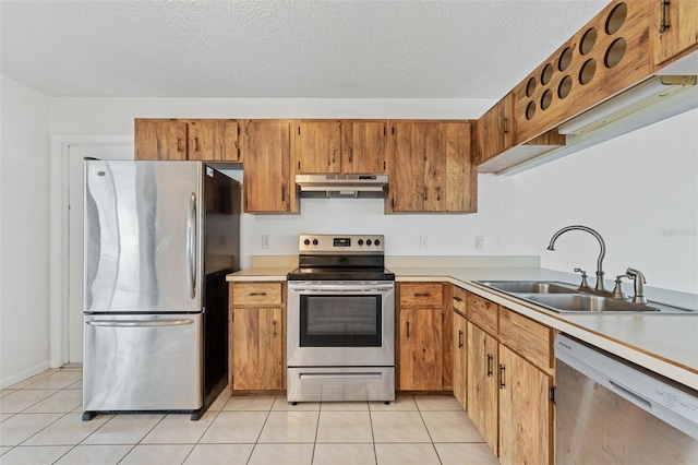 kitchen with a textured ceiling, appliances with stainless steel finishes, light tile floors, and sink