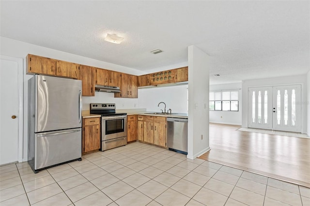 kitchen featuring light hardwood / wood-style floors, french doors, stainless steel appliances, a textured ceiling, and sink