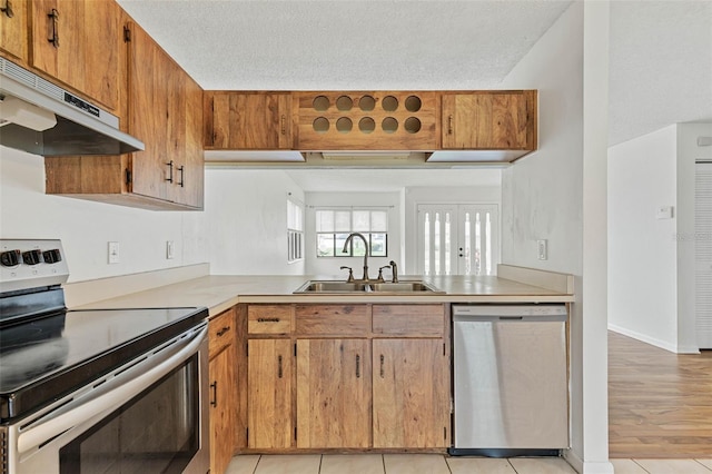 kitchen with stainless steel appliances, light tile floors, a textured ceiling, and sink