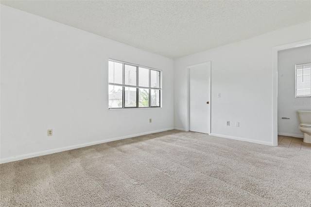 spare room with light colored carpet and a textured ceiling