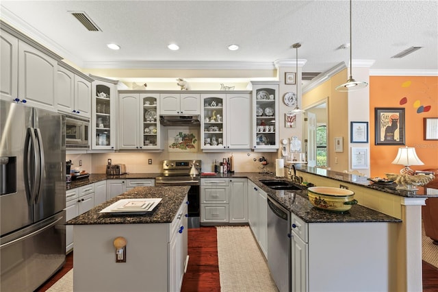 kitchen with kitchen peninsula, stainless steel appliances, sink, pendant lighting, and a kitchen island