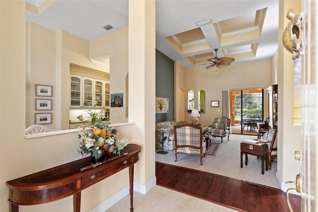 tiled foyer with ceiling fan, beamed ceiling, a high ceiling, and coffered ceiling