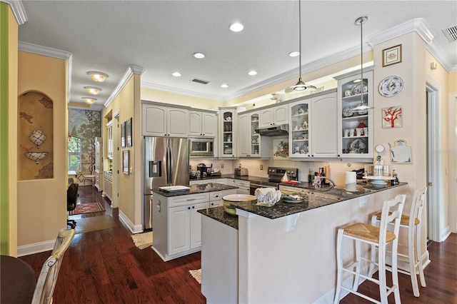 kitchen featuring hanging light fixtures, dark hardwood / wood-style floors, kitchen peninsula, dark stone counters, and appliances with stainless steel finishes