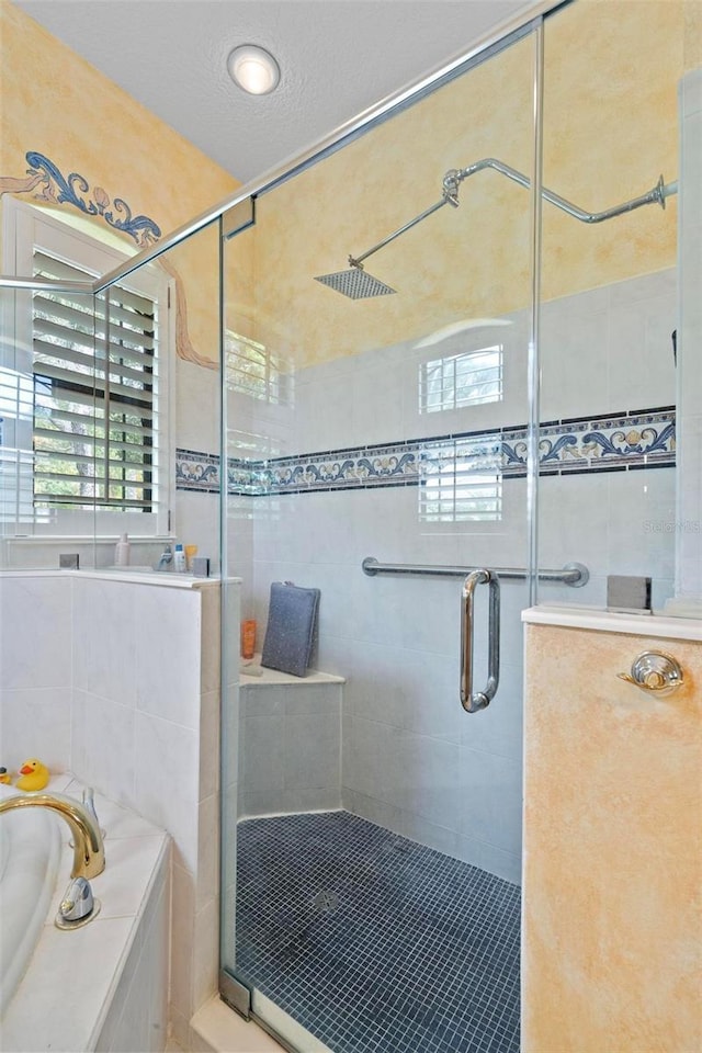 bathroom featuring plus walk in shower and a textured ceiling