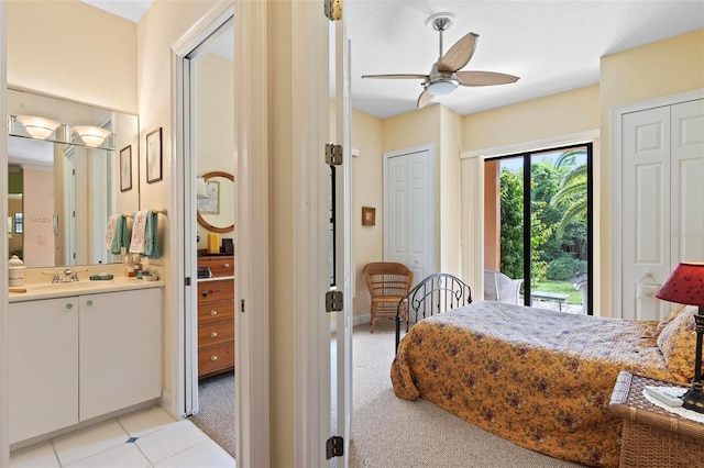 bedroom featuring light carpet, sink, ceiling fan, and two closets