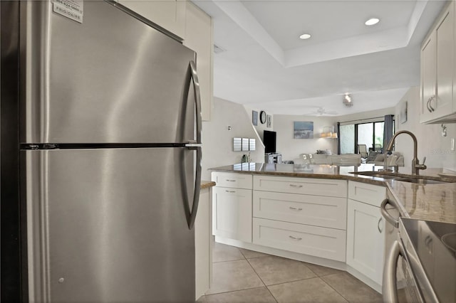 kitchen featuring sink, white cabinets, dark stone counters, and stainless steel fridge