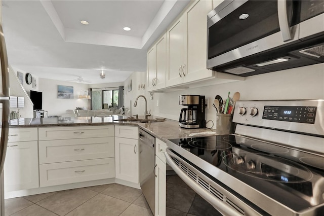 kitchen with appliances with stainless steel finishes, sink, white cabinetry, and dark stone countertops