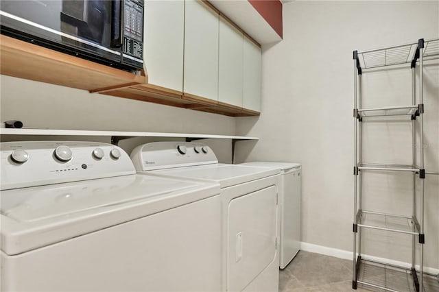 clothes washing area with light tile patterned flooring, cabinets, and separate washer and dryer