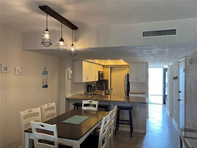 dining space featuring a textured ceiling, sink, and tile patterned flooring