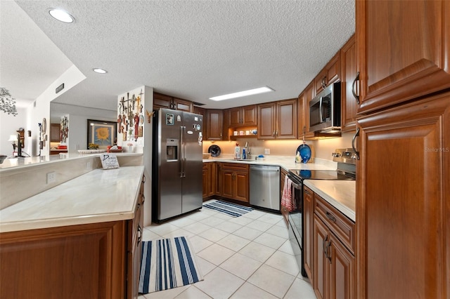 kitchen featuring kitchen peninsula, sink, light tile floors, stainless steel appliances, and a textured ceiling