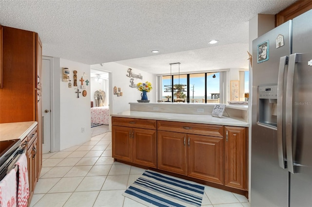 kitchen featuring light tile flooring, hanging light fixtures, a textured ceiling, stainless steel refrigerator with ice dispenser, and stove