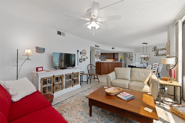 tiled living room with a textured ceiling and ceiling fan with notable chandelier