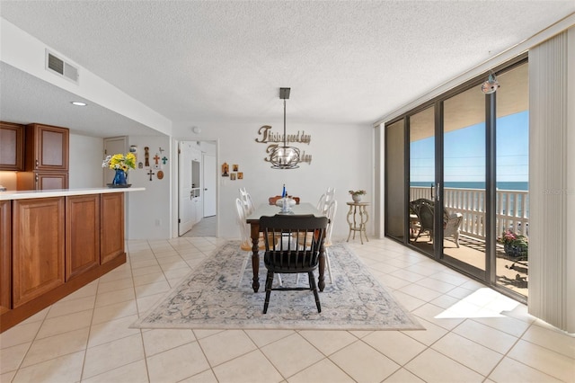 tiled dining room with a wall of windows, a water view, a chandelier, and a textured ceiling