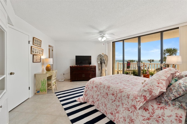 bedroom with expansive windows, access to exterior, ceiling fan, light tile floors, and a textured ceiling