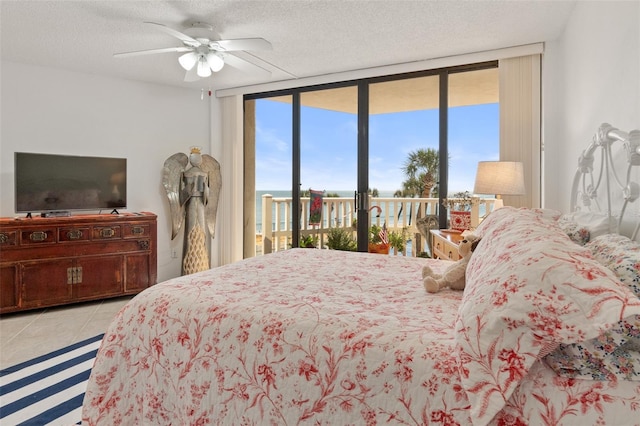 tiled bedroom featuring a textured ceiling, access to exterior, ceiling fan, and a wall of windows