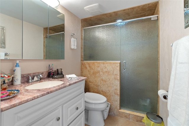 bathroom with tile walls, tile floors, a shower with door, large vanity, and toilet