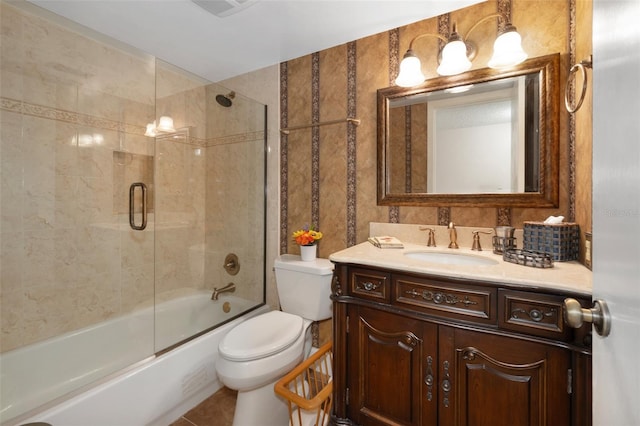 full bathroom with toilet, tile flooring, vanity, and bath / shower combo with glass door