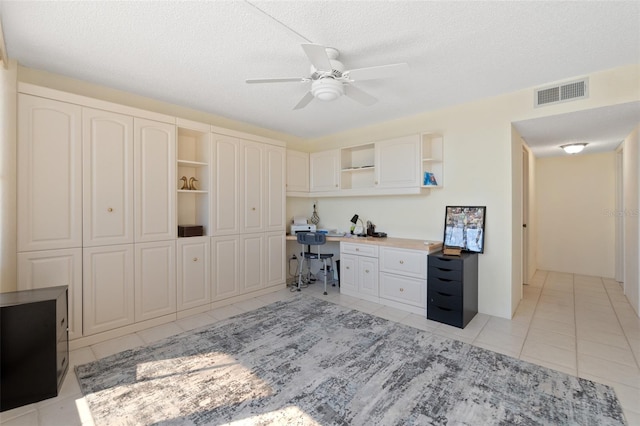 office area with light tile flooring, ceiling fan, and a textured ceiling