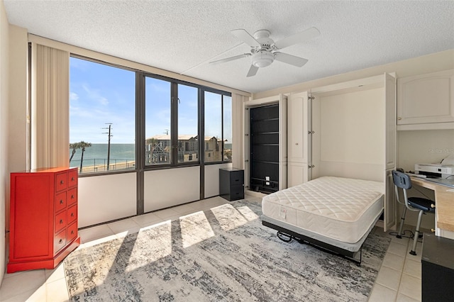 tiled bedroom with a water view, ceiling fan, and a textured ceiling