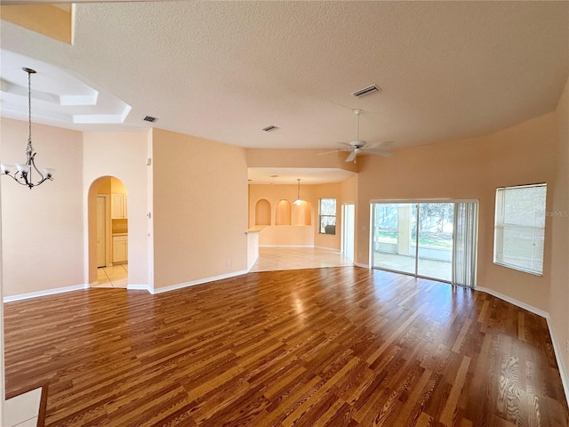 unfurnished room featuring a textured ceiling, a raised ceiling, hardwood / wood-style floors, and ceiling fan with notable chandelier