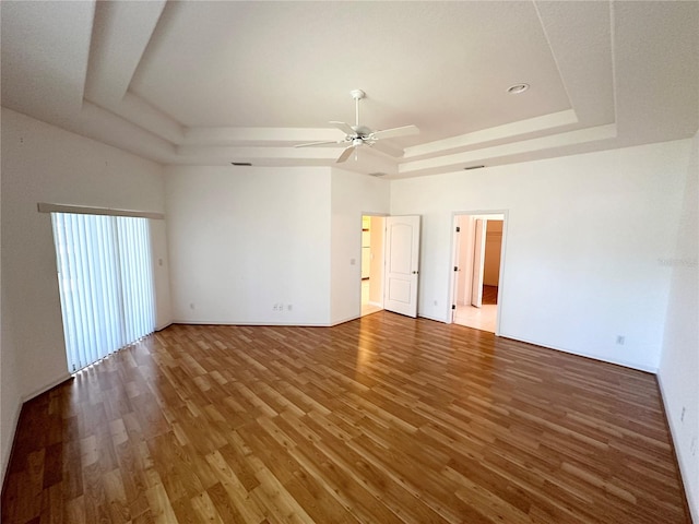 unfurnished room featuring a raised ceiling, dark hardwood / wood-style flooring, and ceiling fan