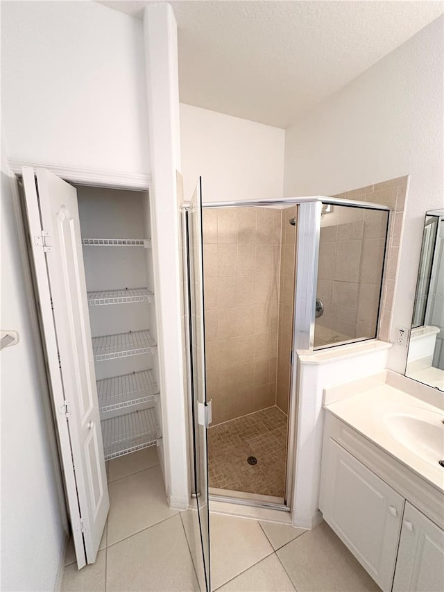 bathroom with a shower with door, tile flooring, a textured ceiling, and vanity