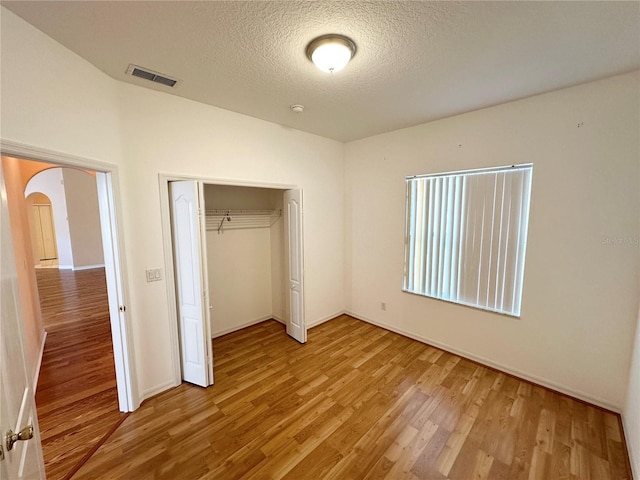 unfurnished bedroom featuring a closet, a textured ceiling, and light hardwood / wood-style floors