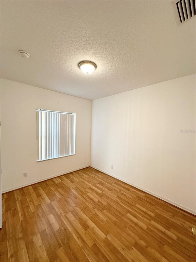 spare room featuring a textured ceiling and light wood-type flooring