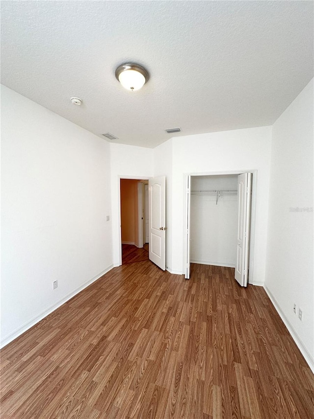 unfurnished bedroom featuring a textured ceiling, a closet, and dark hardwood / wood-style floors