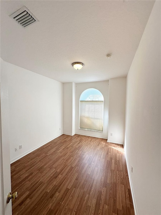 empty room featuring a textured ceiling and dark hardwood / wood-style flooring